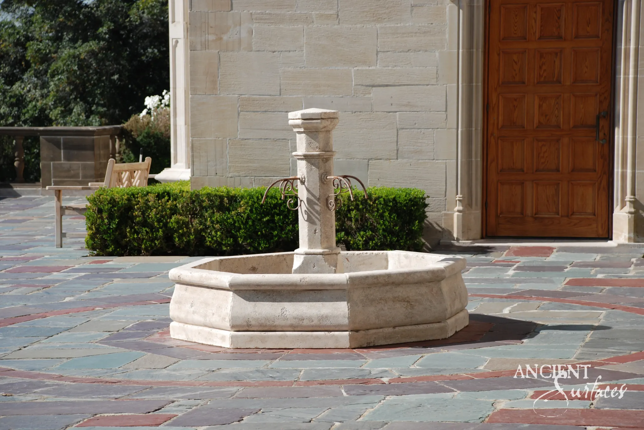 Ancient Surfaces reclaimed octagonal limestone centre fountain with iron spouts on a flagstone entry courtyard