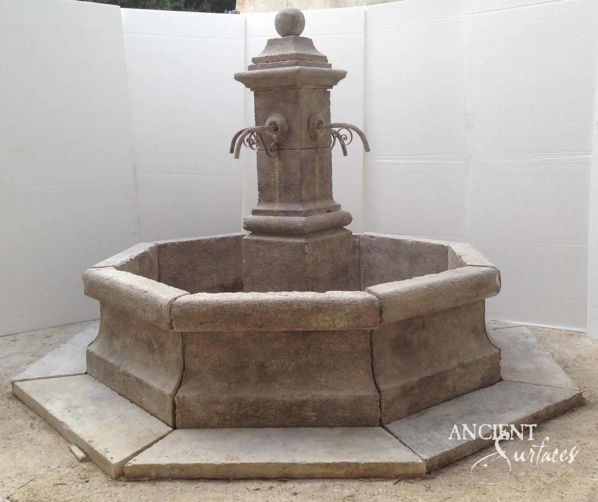 Deeply weathered reclaimed octagonal limestone fountain from Ancient Surfaces with a ball finial pillar and scrolled iron spouts