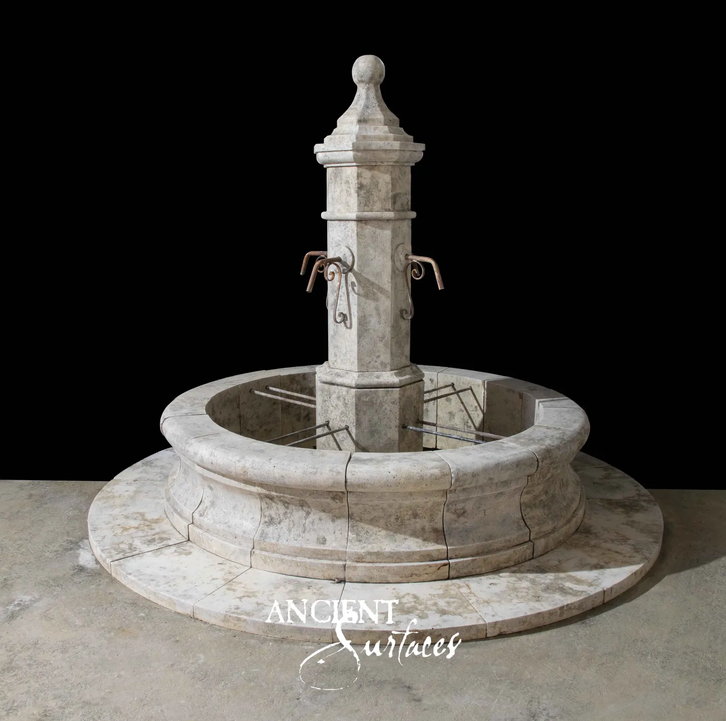 Reclaimed circular limestone fountain from Ancient Surfaces with an octagonal pillar and iron spouts on a wide stepped stone apron